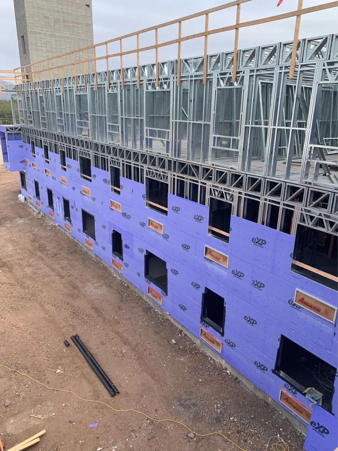 Three-storey steel-framed building with exterior sheathing going on floor by floor
