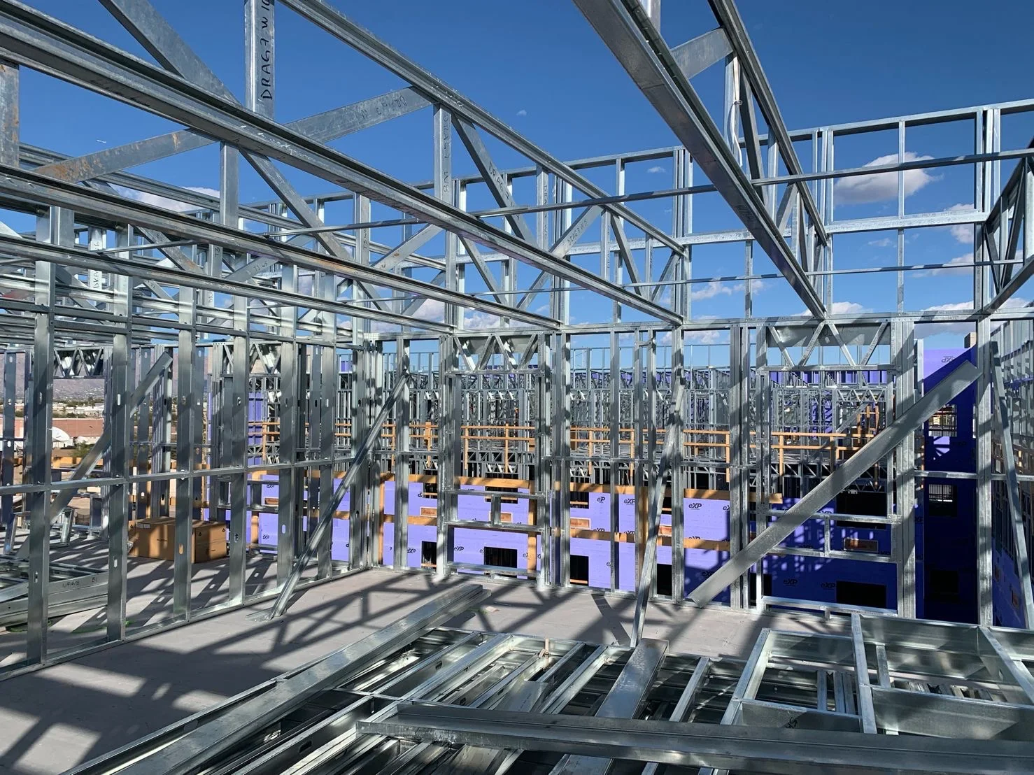 Multifamily building framed in cold-formed steel, upper floor walls and trusses against blue sky
