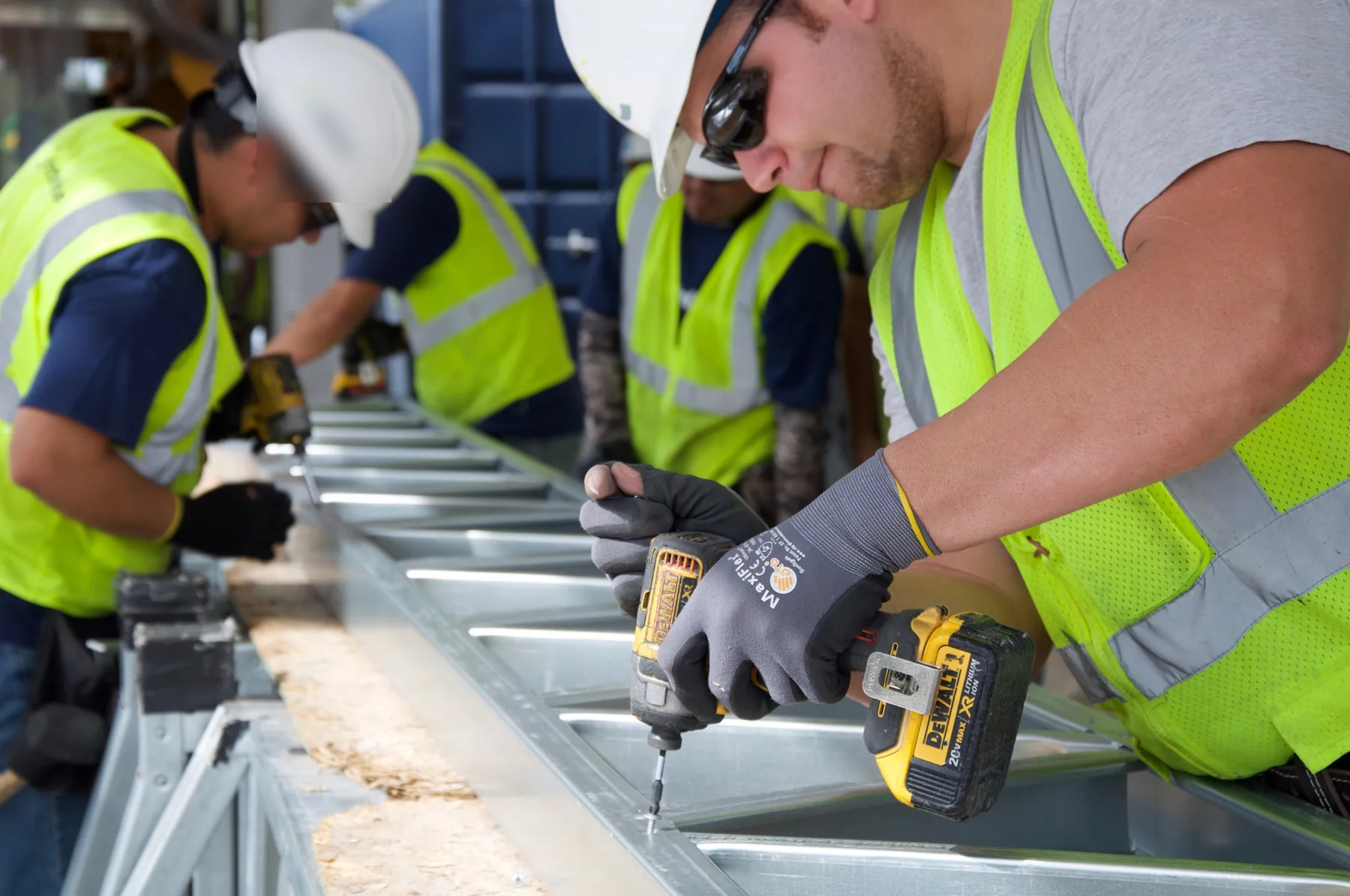 Crew fastening cold-formed steel framing panels on a factory line